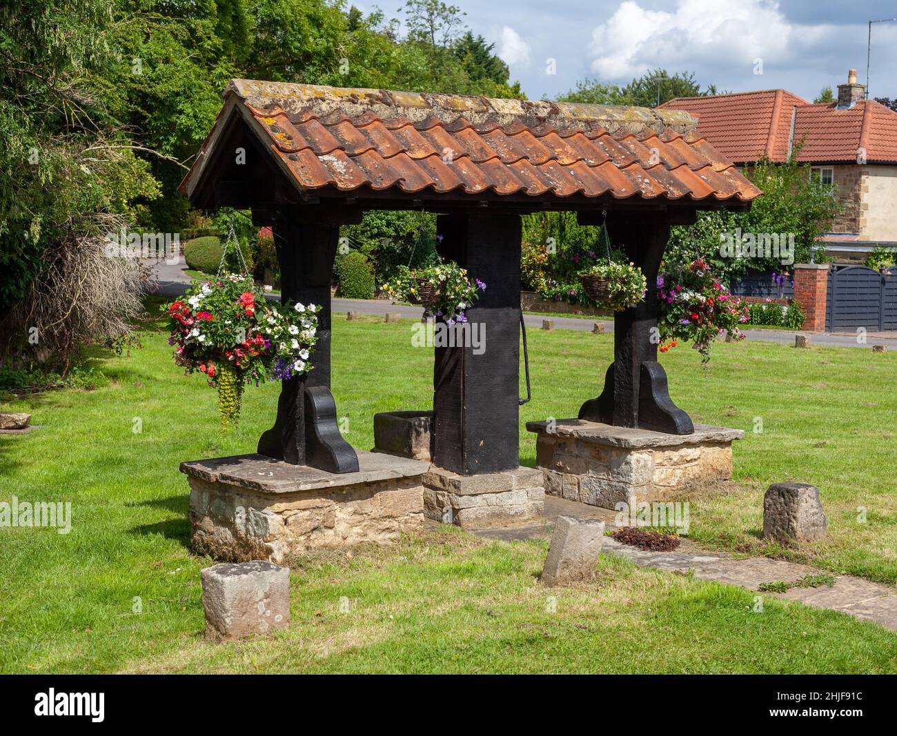 Die mit Blumen geschmückte Dorfpumpe auf dem Grün in Linton, West Yorkshire Stockfoto