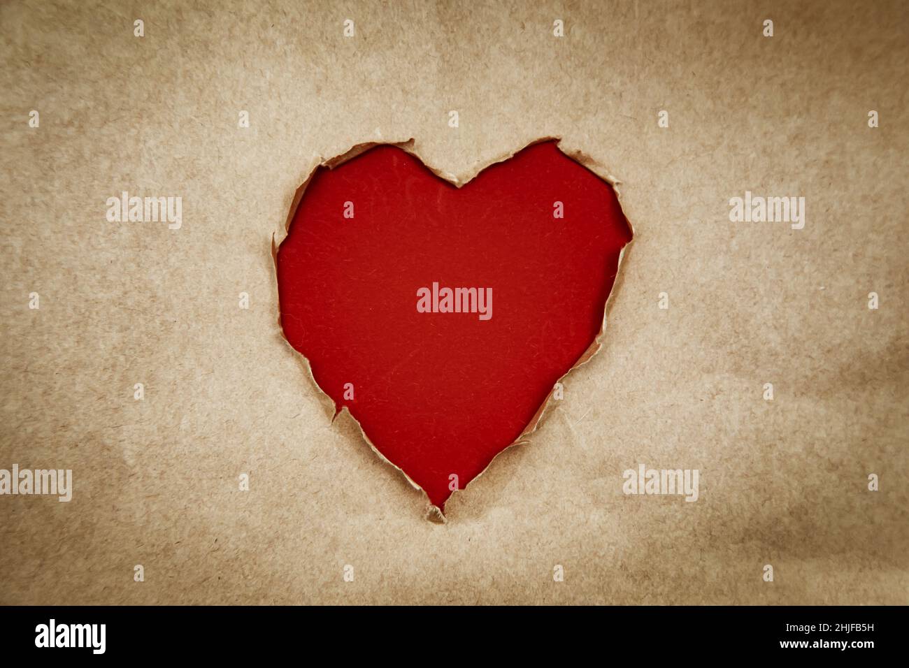 Loch in Form eines Herzens. Recyceltes Kraftpapier. Vintage, Grunge-Stil, Kopierraum. Valentinstag-Konzept. Stockfoto