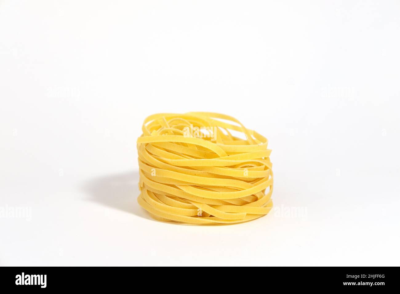 Italienische Pasta. Spaghetti Capellini isoliert auf weißem Hintergrund mit harten Schatten. Pasta in Form von Nestern. Kreatives Foto von Pasta-Essen. Stockfoto