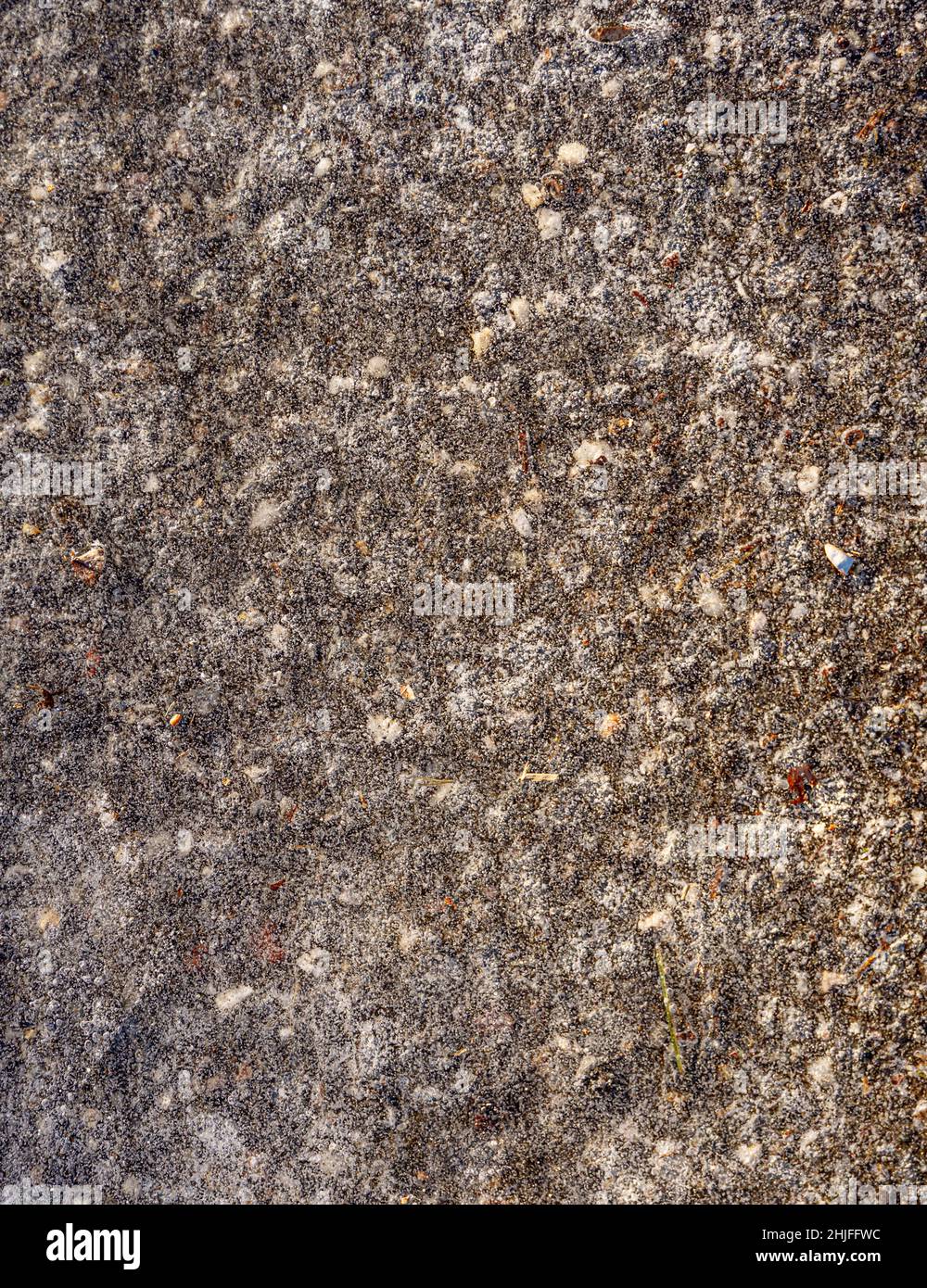 Detail einer dünnen Schicht gefrorenes Wasser, schwarzes Eis auf Asphalt Stockfoto