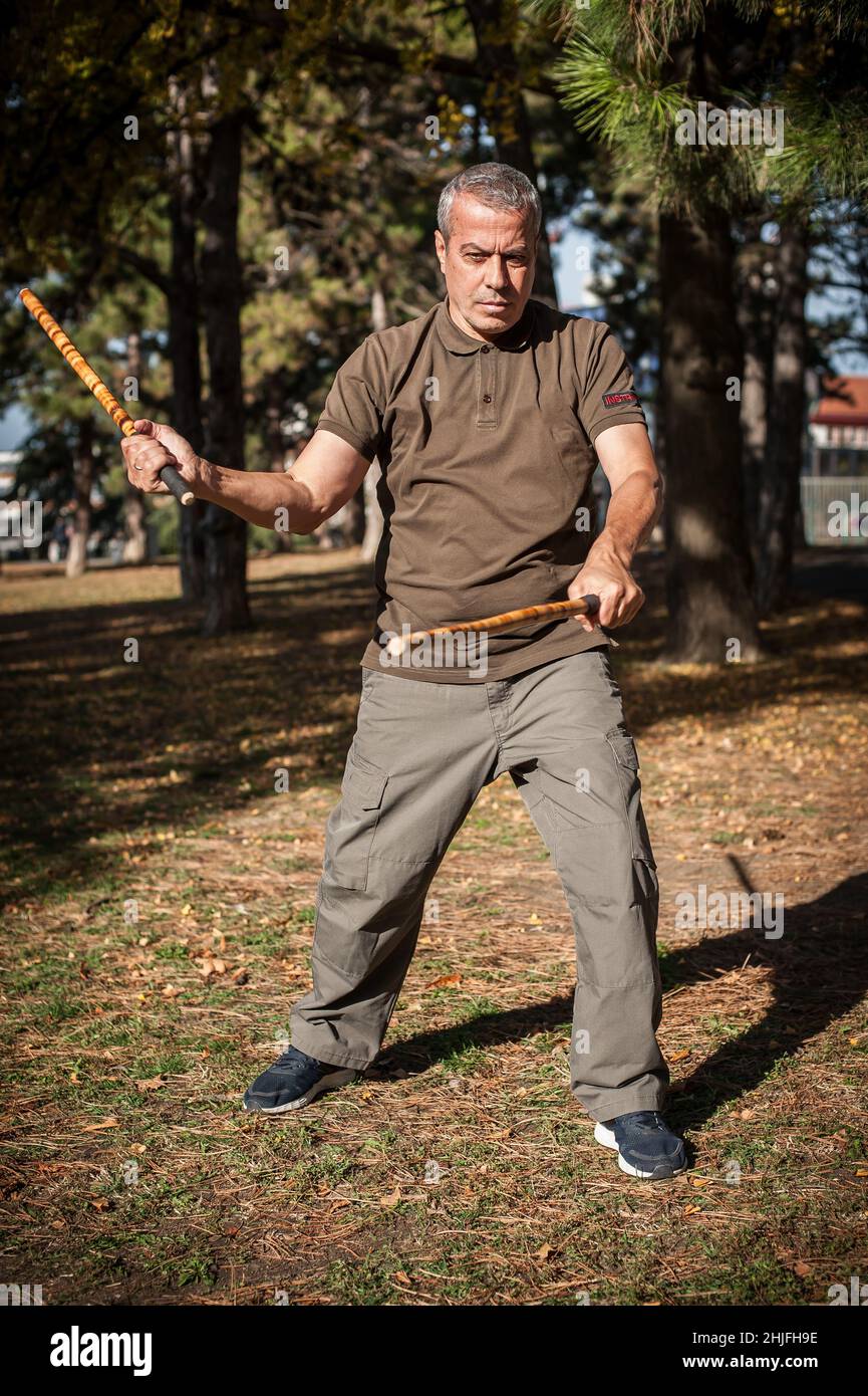 Escrima und Kapap Instruktor demonstriert Stöcke Kampftechniken im öffentlichen Park. Philippinische Kampfkunst. Eskrima. Kali. Stockfoto