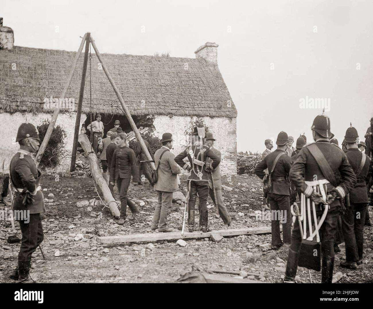 Ein Vintage-Foto der Räumung einer irischen Familie aus dem Jahr 1888 in Moyasta, Grafschaft Clare, in der ein Rammbock verwendet wurde. Vermieter, deren Land mit ärmeren Mietern überfüllt war, wurden jetzt mit hohen Tarifen konfrontiert und viele begannen, die armen Mieter von ihren kleinen Grundstücken zu räumen. Die große Masse an Zwangsräumungen kam im Jahr 1840s, und als die Polizei begann, eine Zählung zu halten, verzeichneten sie insgesamt fast 250.000 Personen, die zwischen 1849 und 1854 offiziell vertrieben wurden. Die Räumungen dauerten bis zum 1890s. Stockfoto