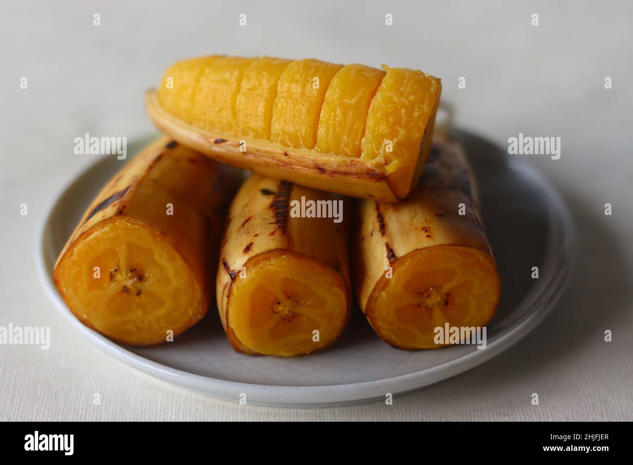 Gedämpfte Banane, vier Haves auf einem Teller gestapelt. Aufgenommen auf weißem Hintergrund Stockfoto