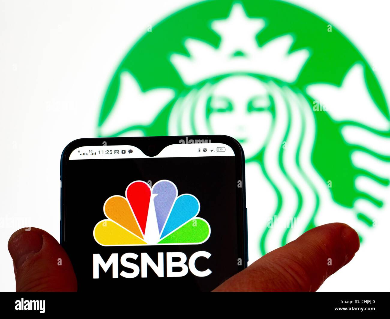 In dieser Abbildung wird das MSNBC-Logo auf einem Smartphone-Bildschirm mit dem Starbucks Kaffee-Logo im Hintergrund angezeigt. Stockfoto