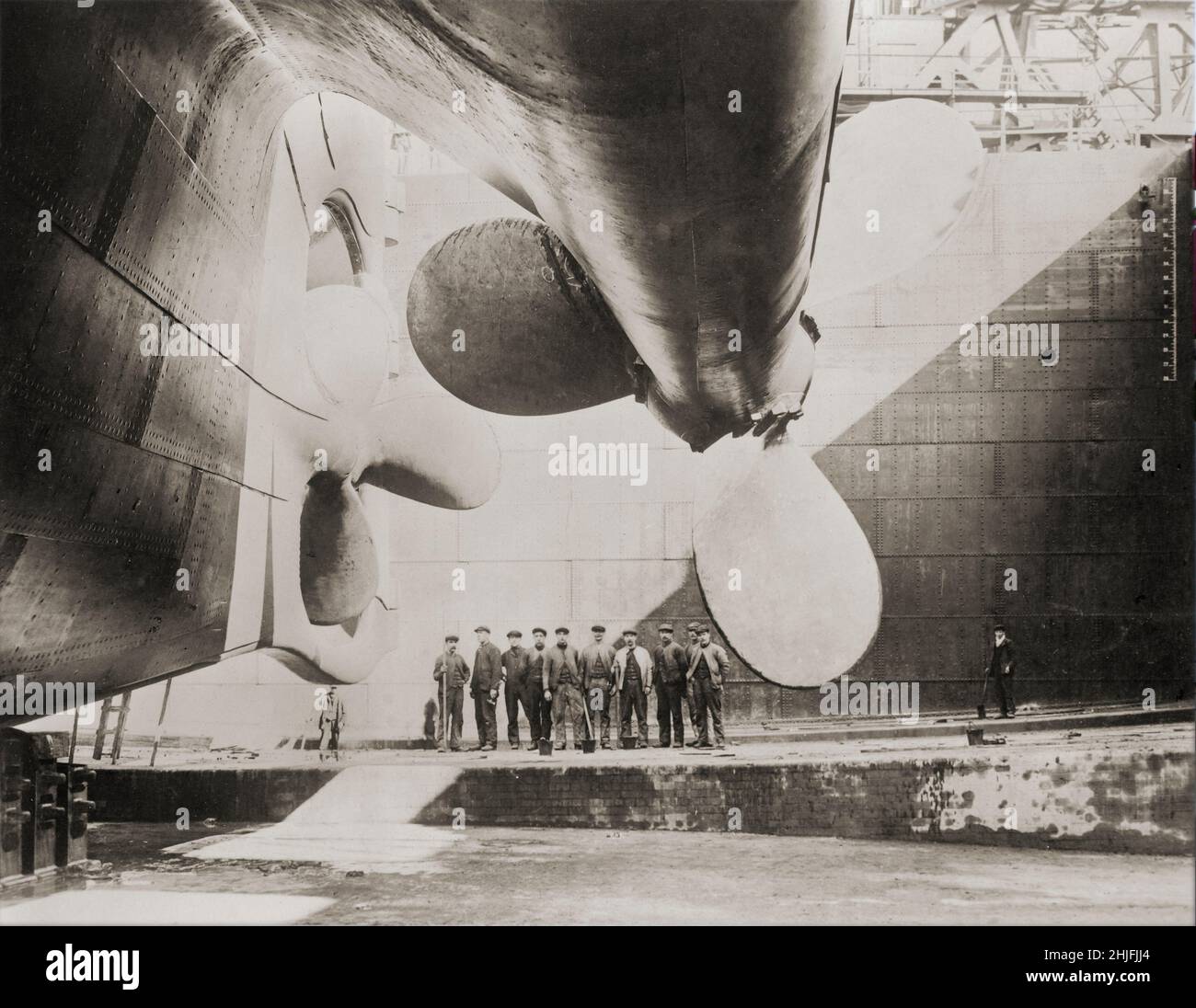 Ein Vintage-Foto von Werftarbeitern und den Propellern, die RMS Titanic, das britische Passagierflugzeug, vor seinem Start im Jahr 1911 angetrieben haben. Betrieben von der White Star Line, die am 15. April 1912 im Nordatlantik versank, nachdem sie während ihrer Jungfernfahrt von Southampton, Großbritannien, nach New York City einen Eisberg geschlagen hatte. Von den geschätzten 2.224 Passagieren und der Besatzung an Bord starben mehr als 1.500, was den Untergang wahrscheinlich zu einem der tödlichsten für ein einziges Schiff bis zu dieser Zeit machte. Stockfoto