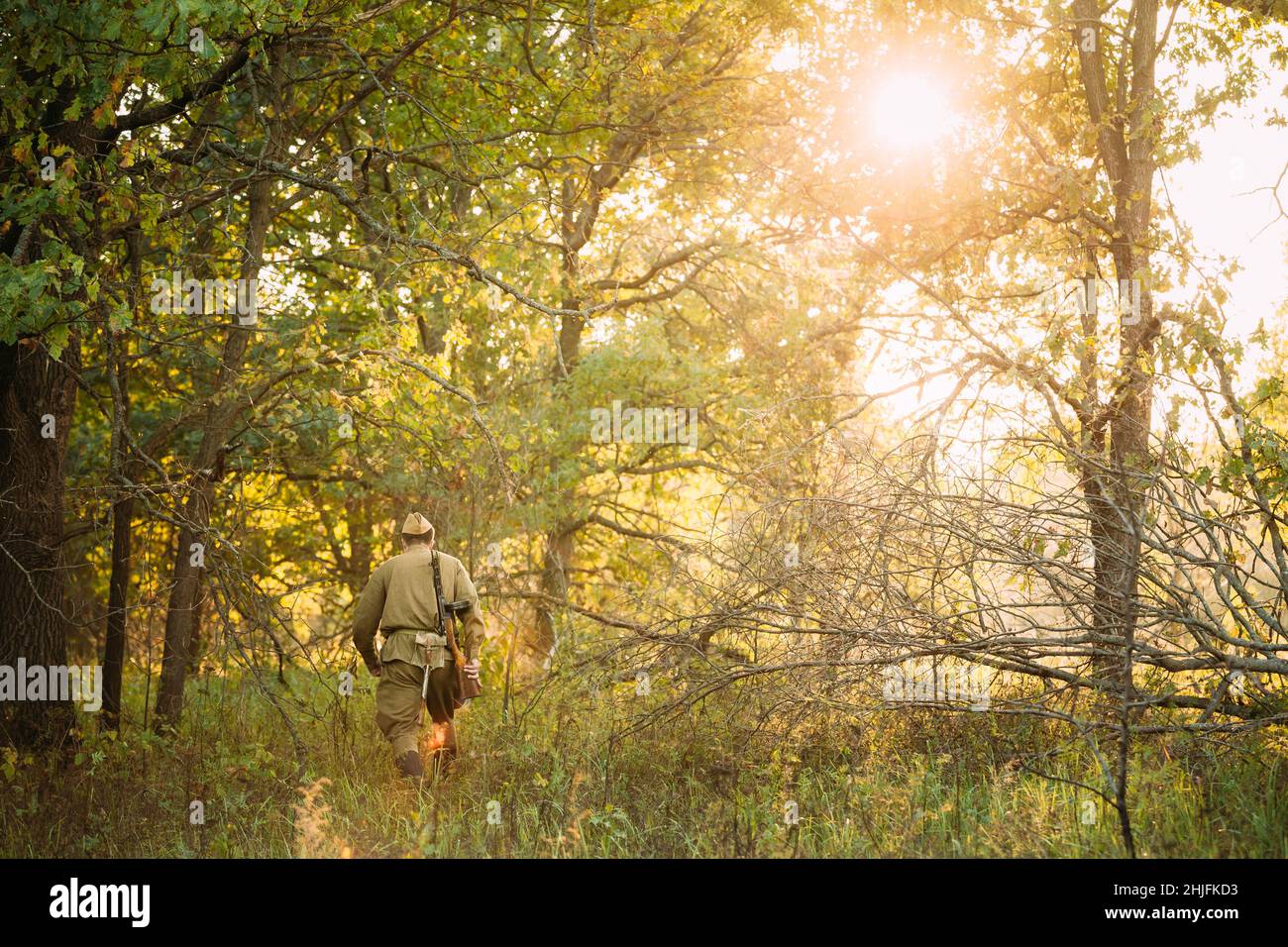 Re-enactor verkleidet als Soldat der russischen sowjetischen Roten Armee des Zweiten Weltkriegs, der mit Waffen durch den Herbstwald läuft. Soldat des Zweiten Weltkriegs WW2 Mal Stockfoto