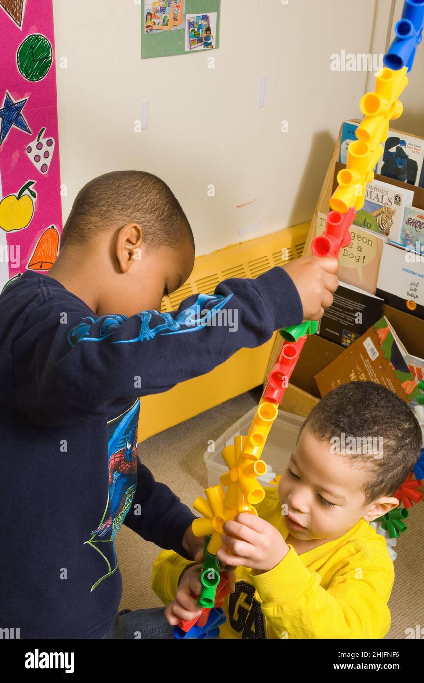 Bildung Vorschule Klassenzimmer 3-4 Jahre alt zwei Jungen, die ein sehr hohes Stück aus der Verbindung von bunten Kunststoffteilen konstruieren Stockfoto