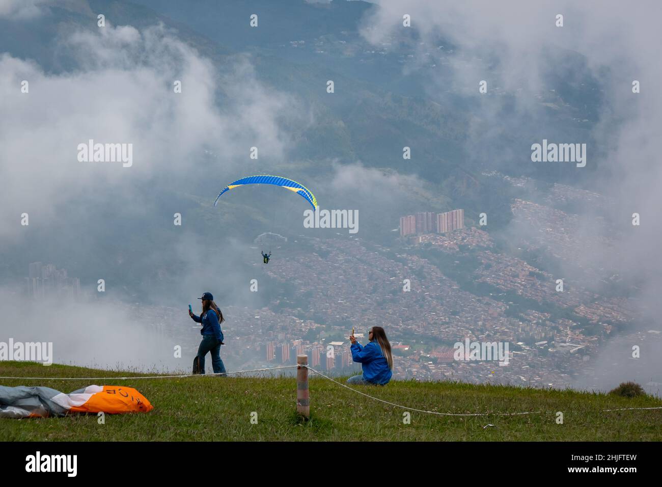 Belmira, Antioquia, Kolumbien - November 20 2021: Frauen machen Fotos und Filmen von den Gleitschirmfliegern beim Start und Fliegen zwischen den Bergen Stockfoto