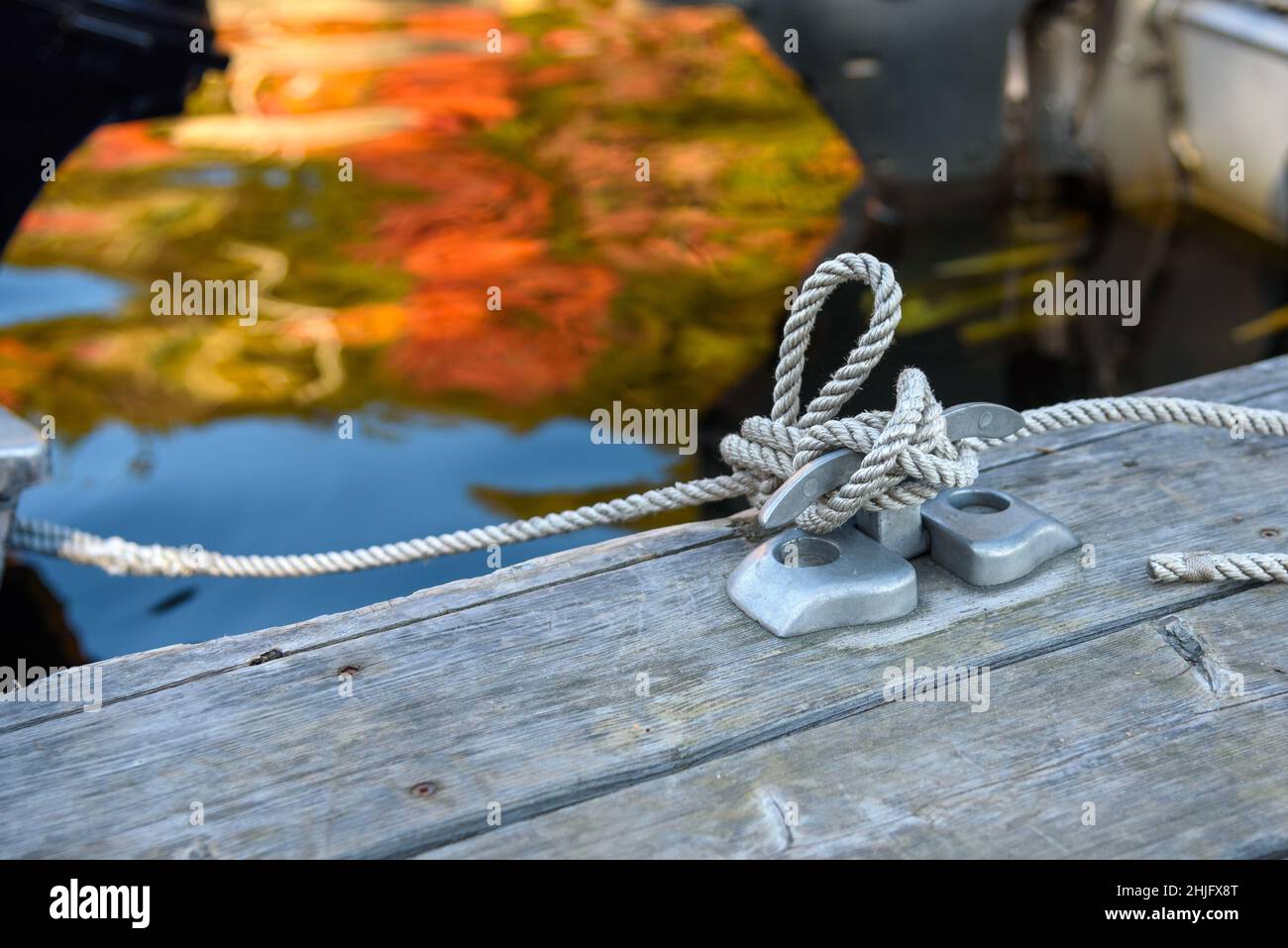 Nahaufnahme eines an einen Stahlstrang geknüpften Seils in einer Marina an einem sonnigen Herbsttag Stockfoto