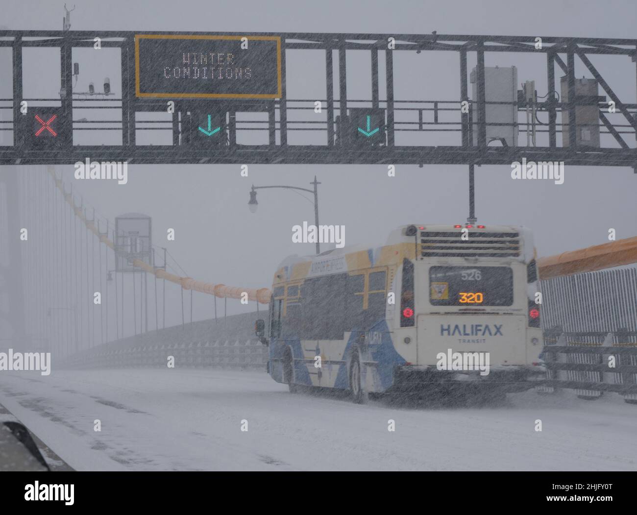 Halifax, Nova Scotia, Kanada. Januar 2022. Transit Bus 320, in reduziertem Verkehr auf der MacDonald-Brücke nach Halifax mit fast Null Sicht während eines Winterschneestürms Stockfoto