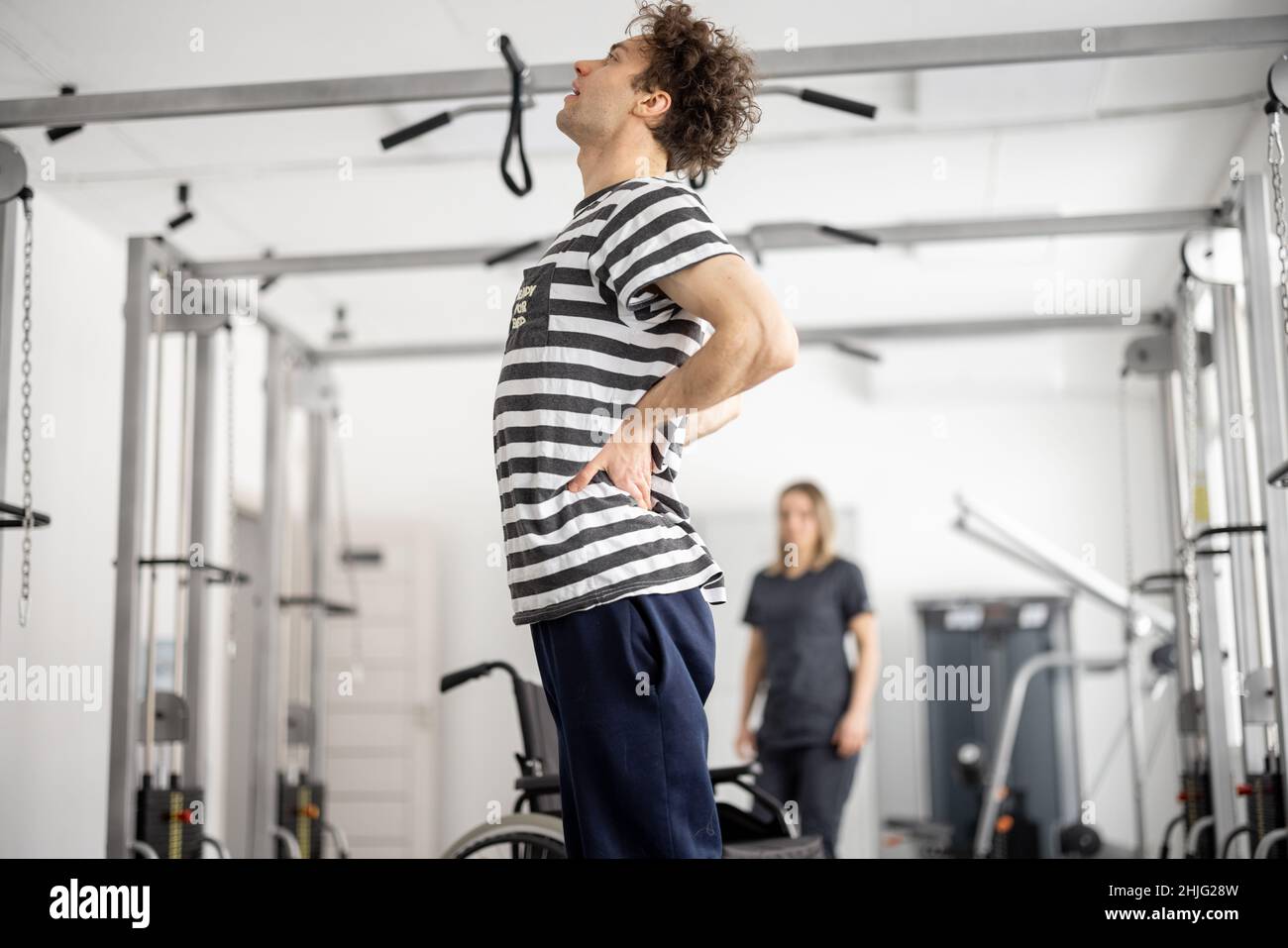 Typ, der Rückenschmerzen beim Training in einem Rehabilitationszentrum hat Stockfoto