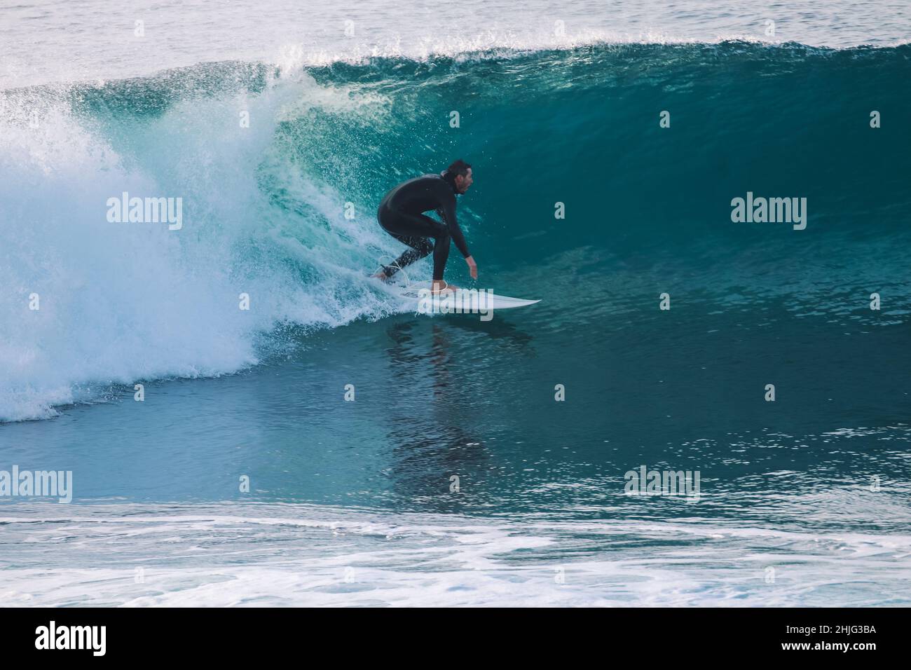 Surfer macht ein Manöver in einer perfekten Welle bei Sonnenuntergang Stockfoto