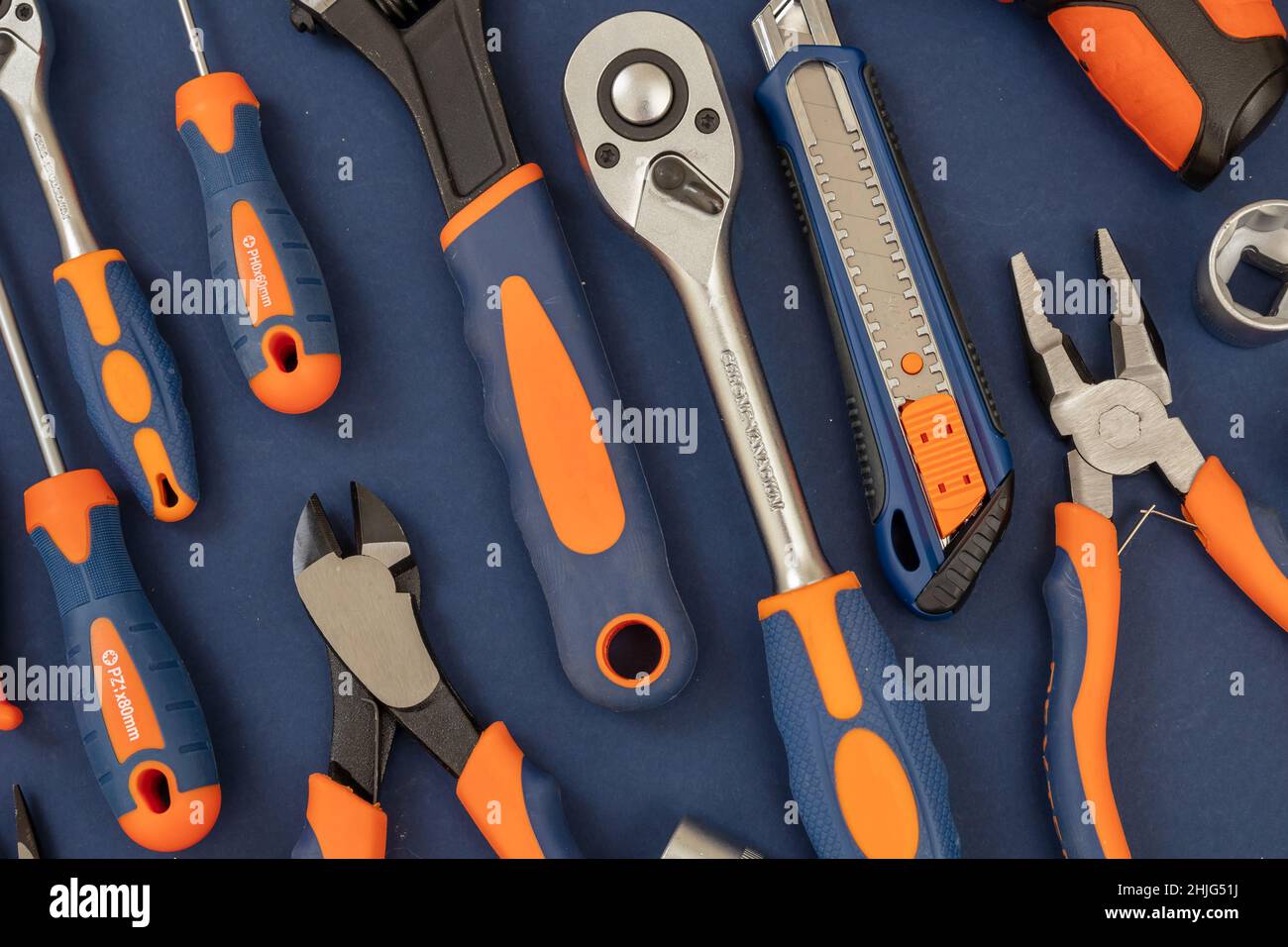 Arbeitswerkzeug auf blauem Hintergrund. Handwerkzeug neues Set mit orangefarbenem Gummigriff für Reparatur und Konstruktion, flach liegend Stockfoto