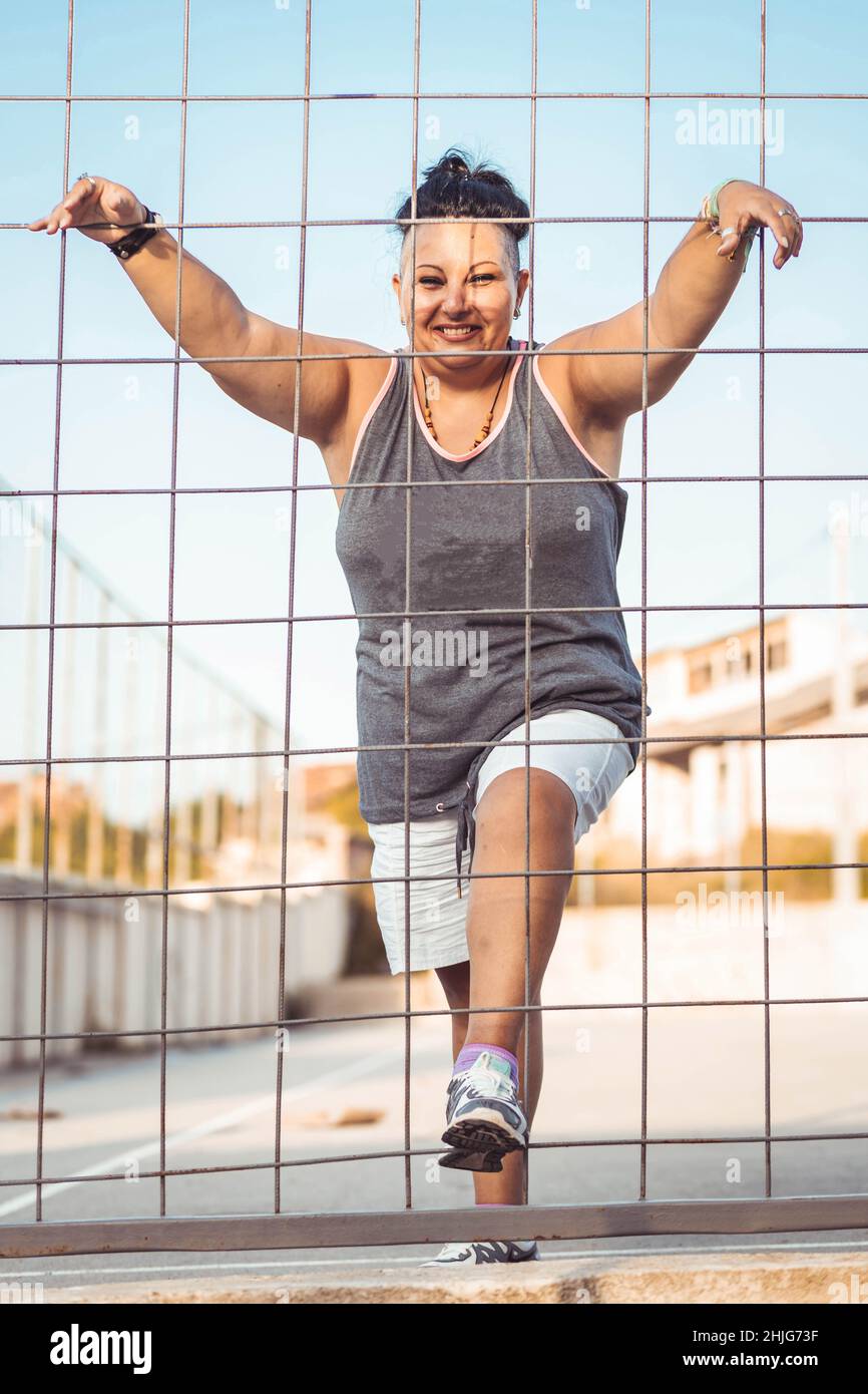 Positive Frau mittleren Alters mit Cherokee Haarschnitt. Schauen Sie durch den Draht Stockfoto