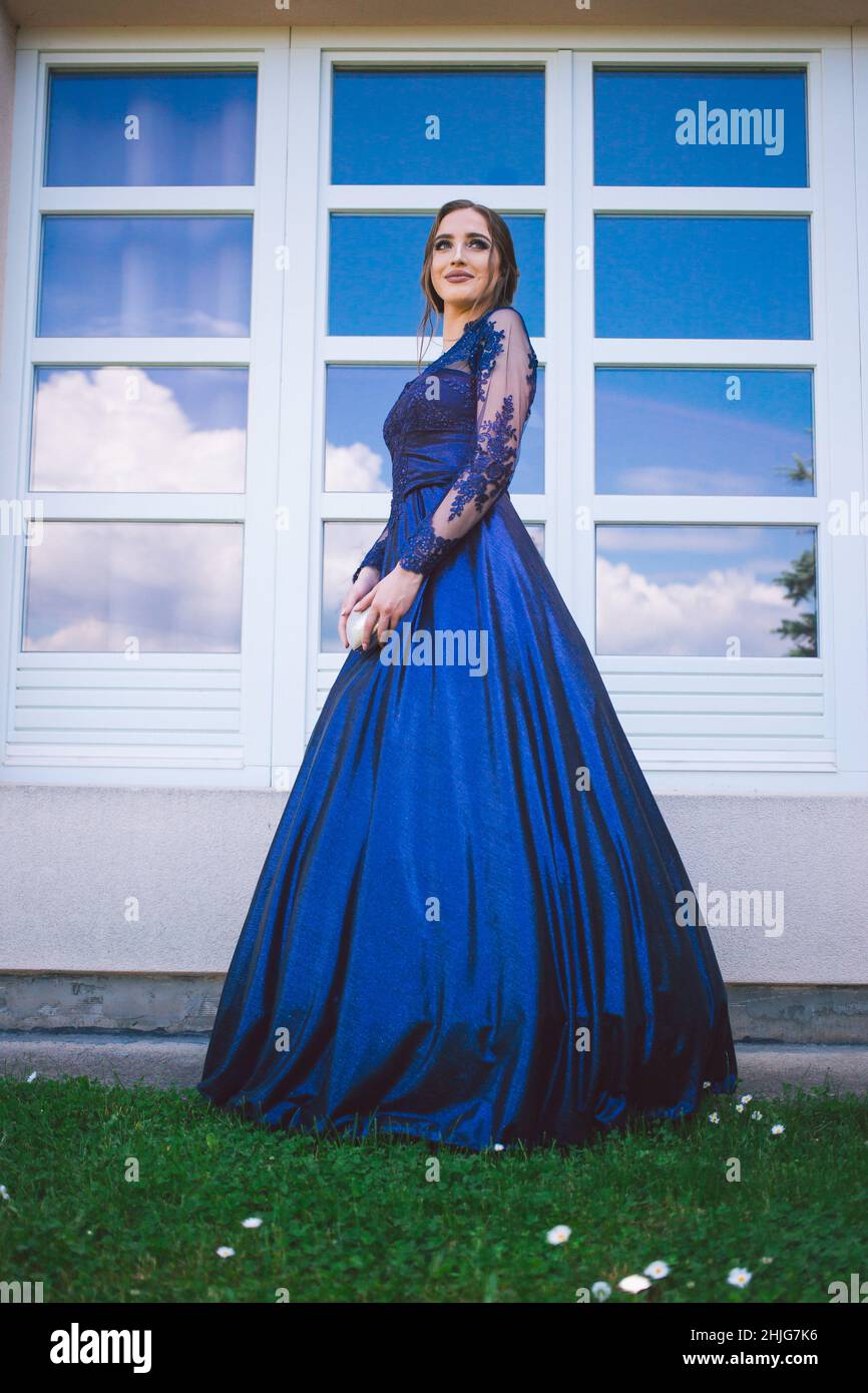 Schönes Mädchen in glamourösen ultramarinen Kleid stehen am Fenster. Bereit für ihre Abschlussball Nacht. Stockfoto