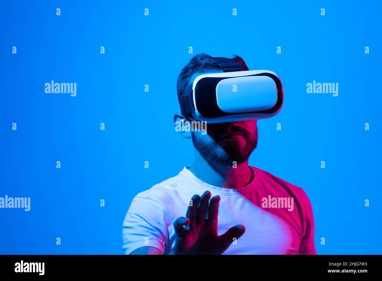 Staunender junger bärtiger Mann, der eine High-Tech-Smart-VR-Brille trägt,  360-Grad-Videos ansieht oder ein Videospiel im Metaverse spielt  Stockfotografie - Alamy