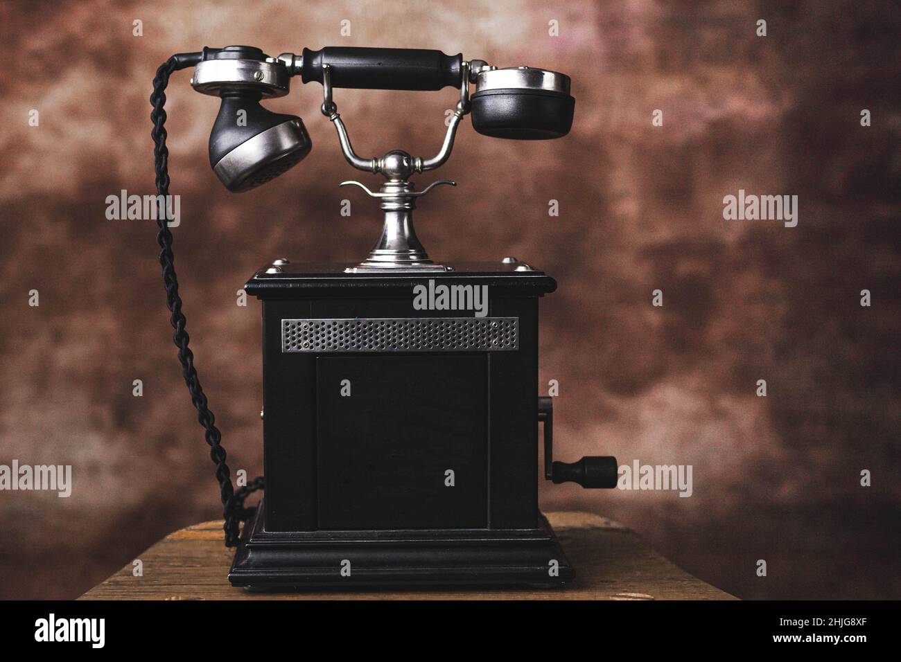 Altes schwarzes, antikes Telefon auf dem braunen Hintergrund isoliert Stockfoto