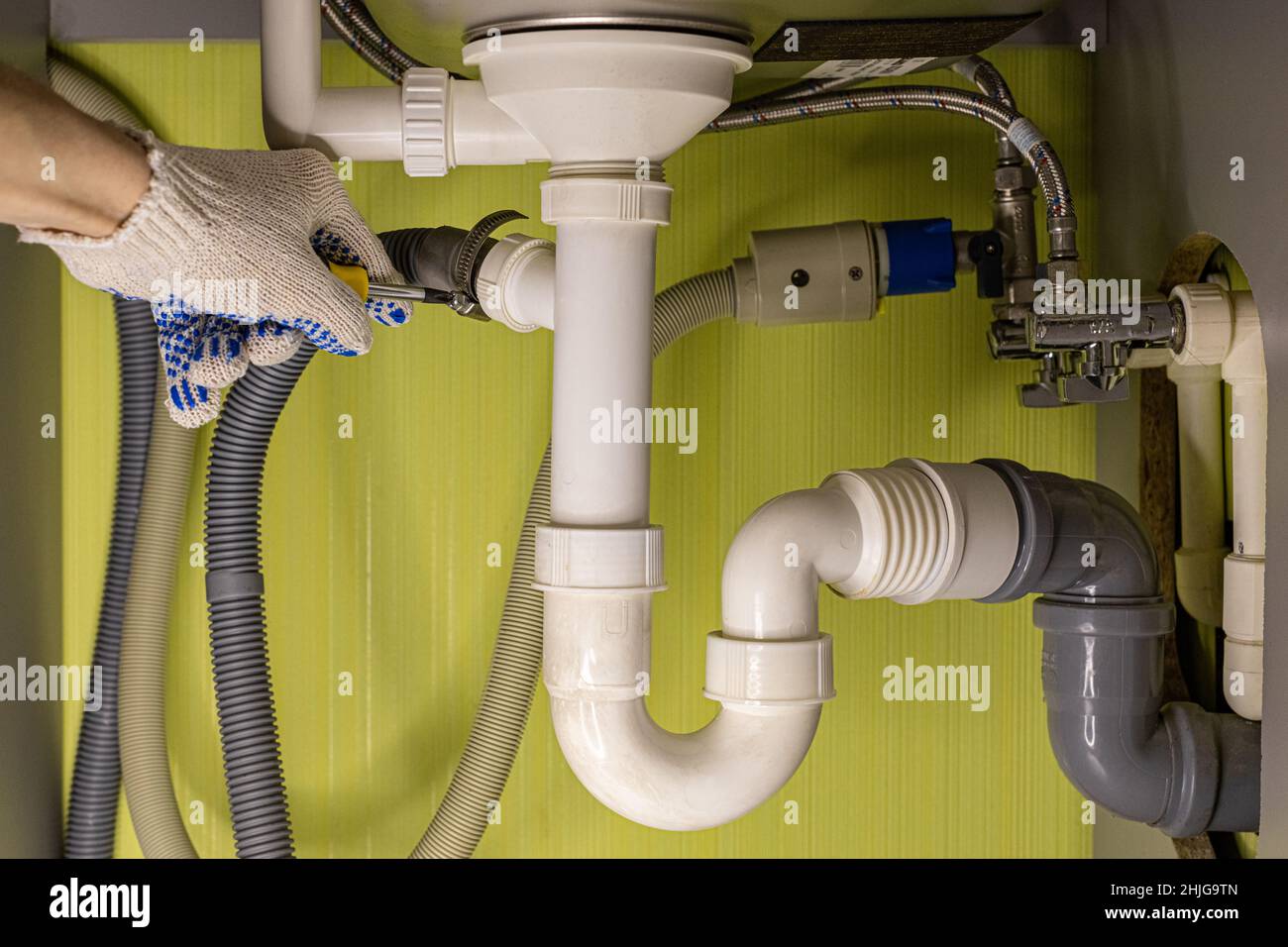 Die Hand zieht einen Bolzen an, während der Abfluss unter dem Waschbecken repariert wird. Hochwertige Fotos Stockfoto