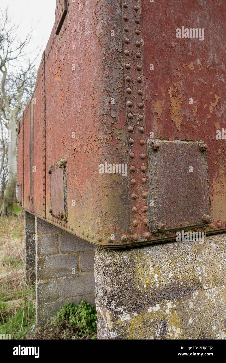 Detaillierte Nahaufnahme eines rostigen Wassertanks aus rotbraunem Eisen, der auf Betonblöcken aufgesetzt ist Stockfoto