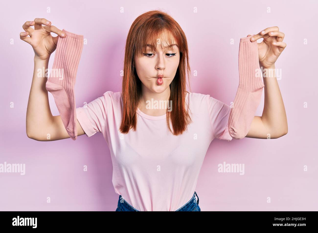 Rotschopf junge Frau mit Socken machen Fisch Gesicht mit Mund und Augen schielen, verrückt und komisch. Stockfoto