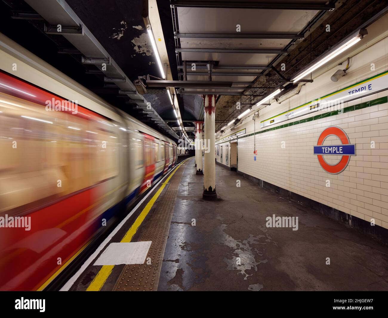 London, Greater London, England, Januar 5th 2022: Innenansicht der U-Bahn Temple, auch bekannt als U-Bahn-Station, wenn ein Zug eine Plattform mit Bewegungsunschärfen passiert. Stockfoto