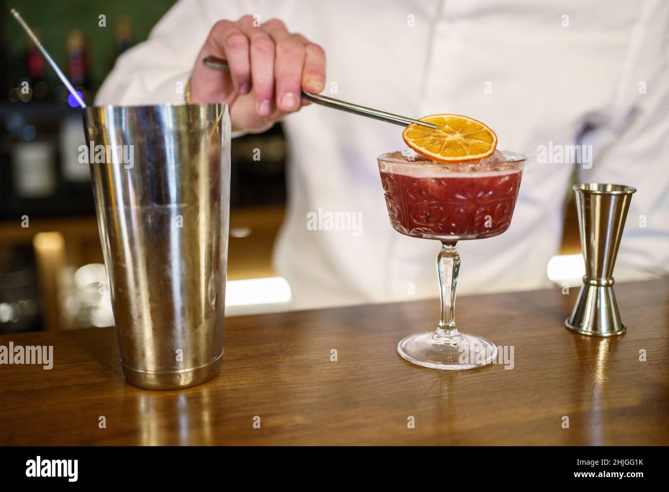 Crop Barman garniert Cocktail mit Zitrusscheibe Stockfoto