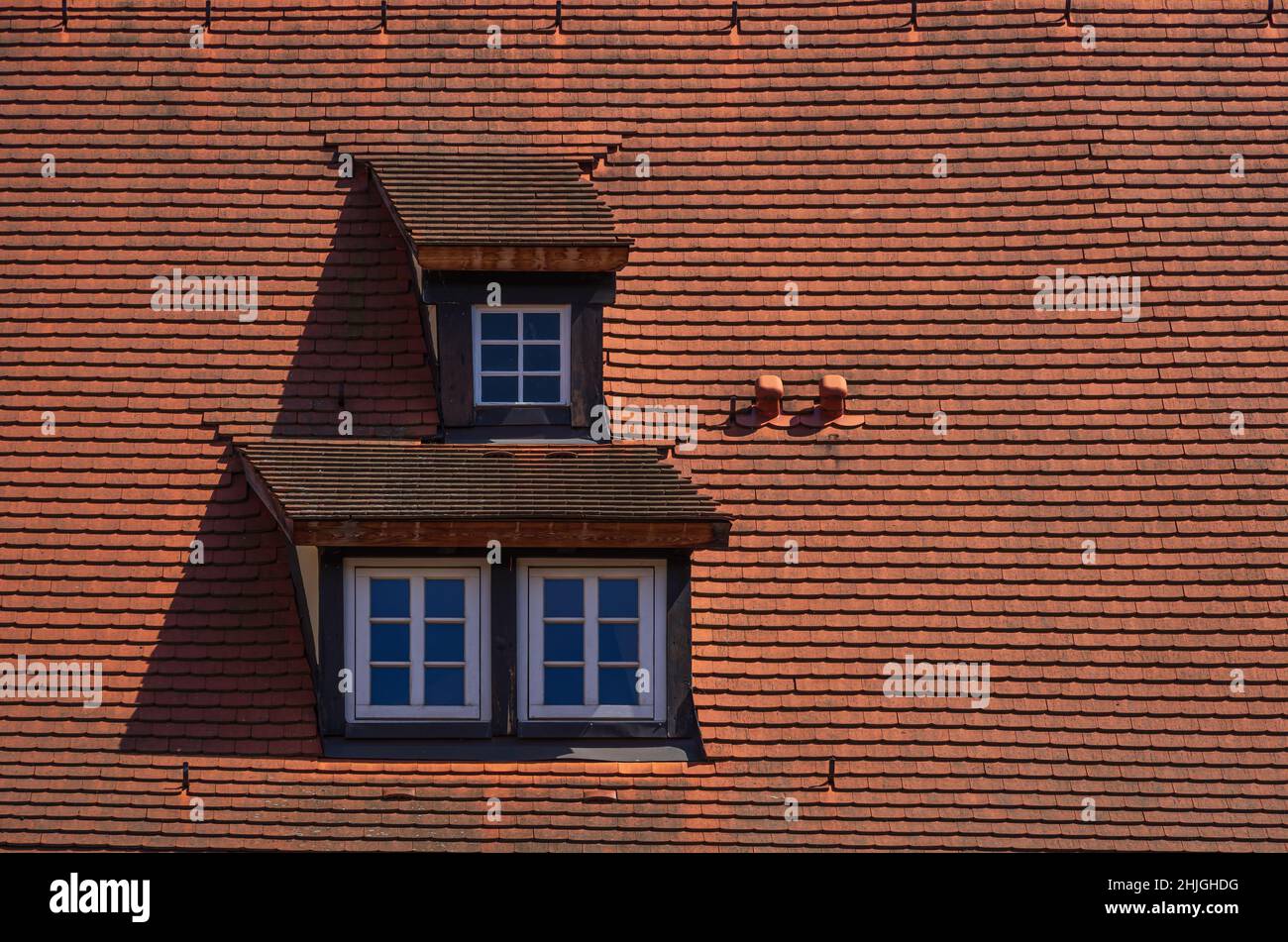 Drei Dachgauben mit Mansardenfenstern in einer mit roten Fliesen überzogenen Dachkonstruktion. Stockfoto