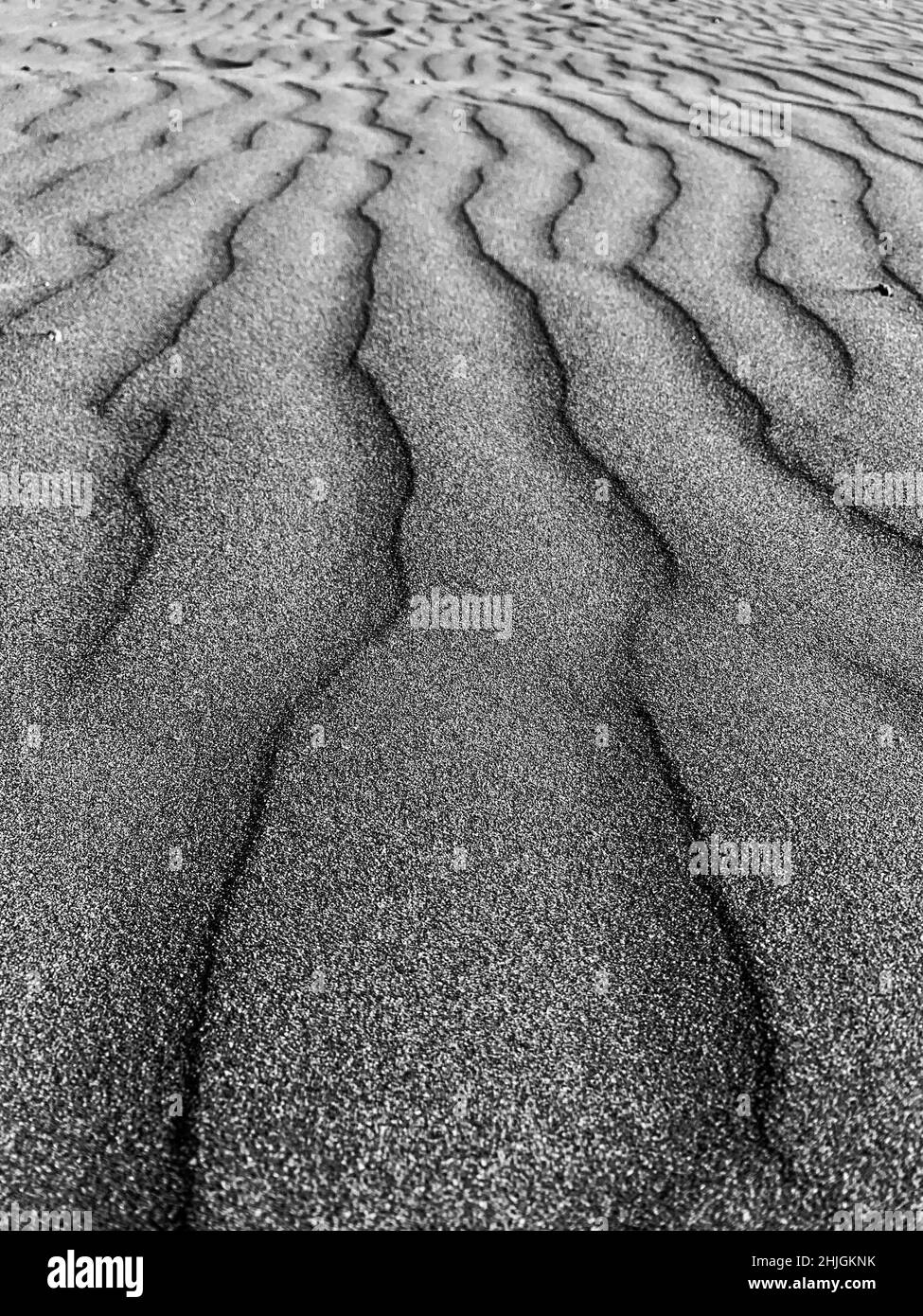 Schwarzer Sandhintergrund. Dunkle Sandwellen Stockfoto