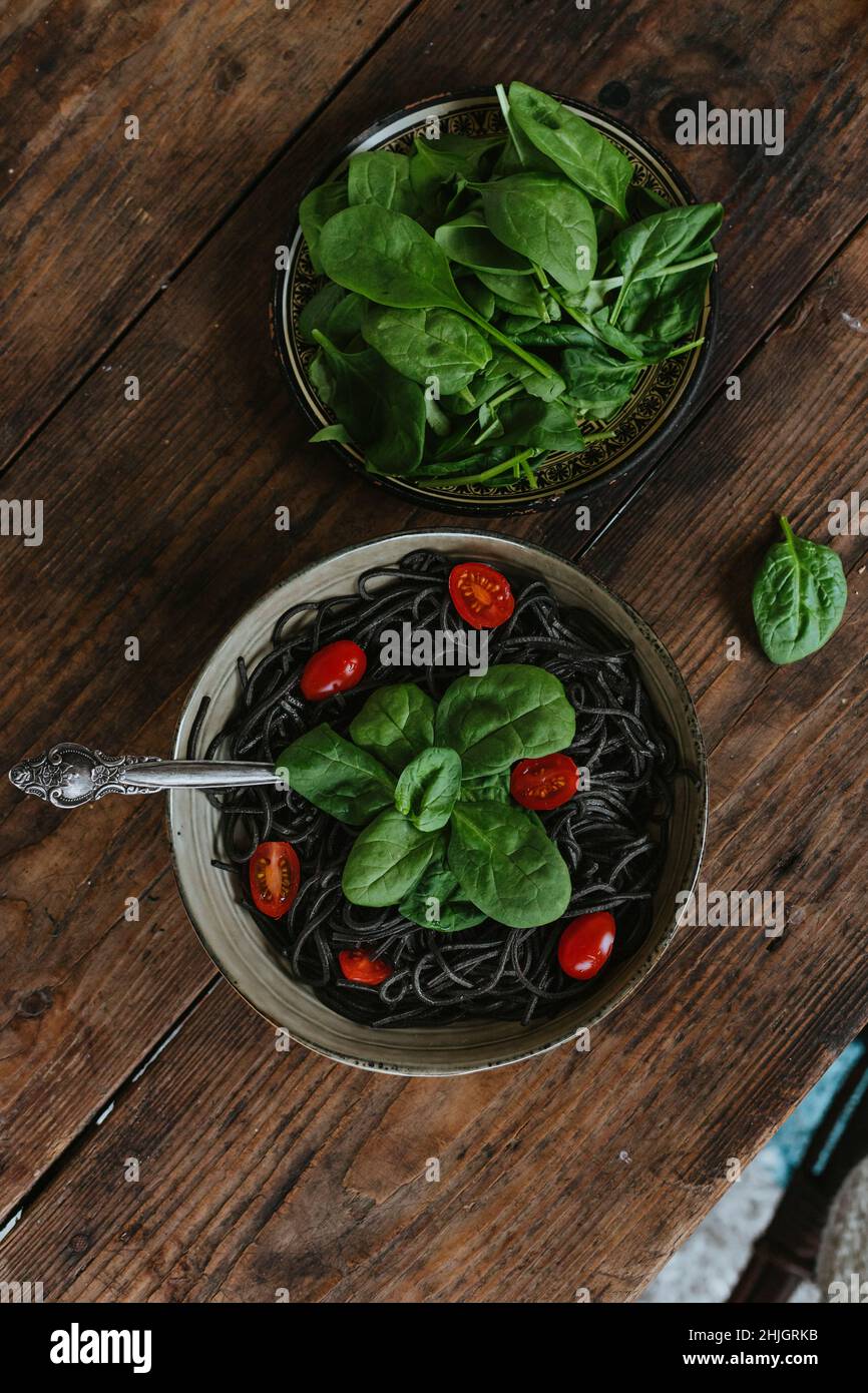 Gekochte Spaghetti mit Tintenfischfarbe, mit Käse und Gemüse arrangiert Stockfoto
