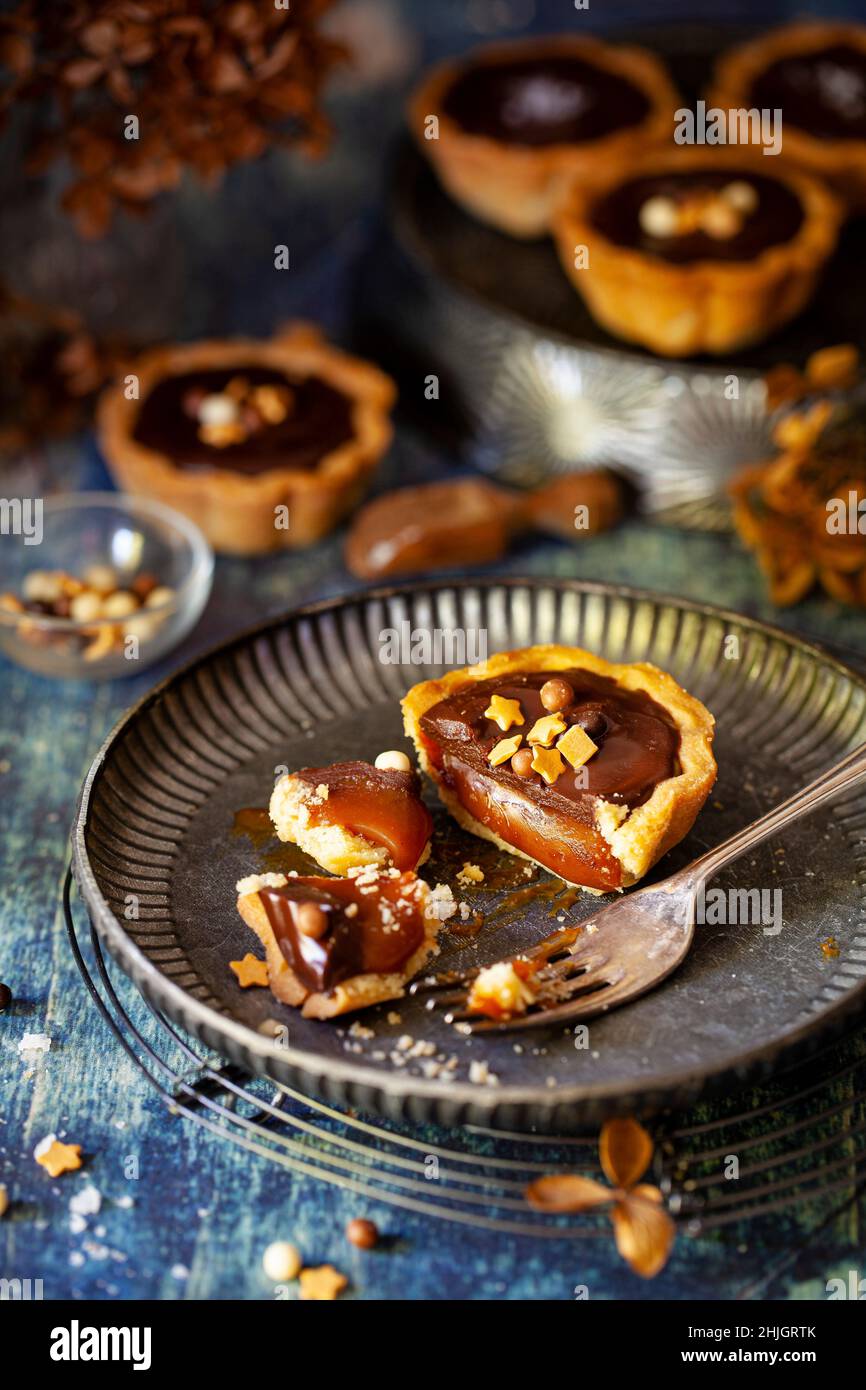 Ein Teil gegessen Schokolade Karamell Tarte auf einem Teller mit Schokoladenkugeln und goldenen Sternen gekrönt Stockfoto