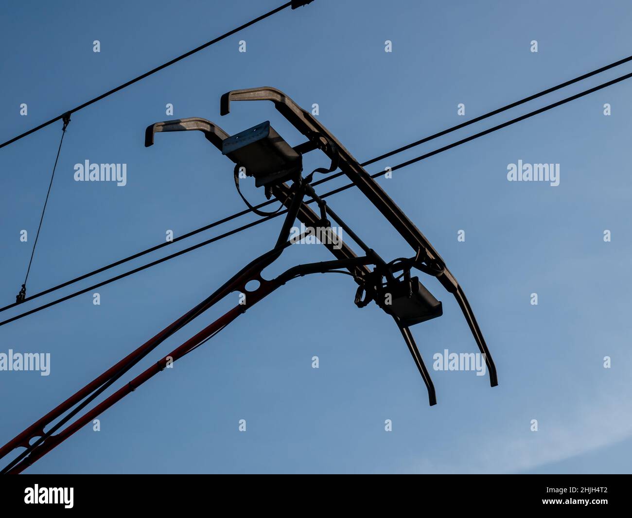 Pantograph eines Zuges, der auf einer elektrischen Linie auf blauem Himmel-Hintergrund verbindet Stockfoto