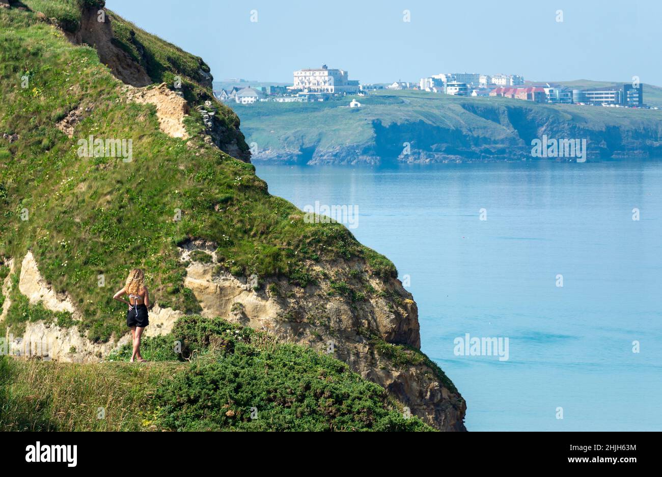 Newquay,Cornwall,England,Vereinigtes Königreich-Juni 21st 2021: Eine junge Frau versucht, ein Signal auf ihr Telefon zu bekommen, während sie die ruhige Bucht von der Klippe aus überblickt Stockfoto