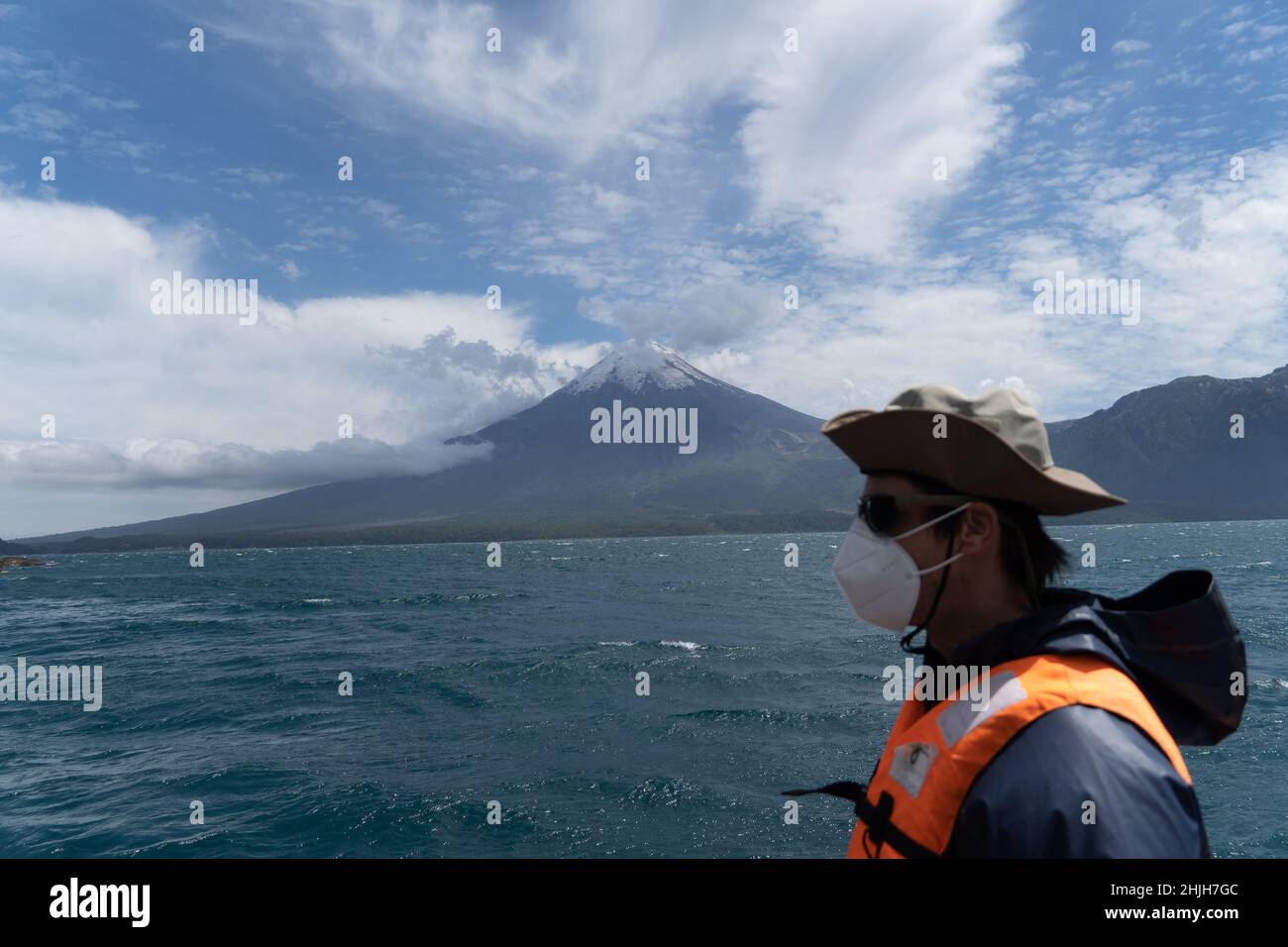 Petrohue, Los Lagos, Chile. 29th Januar 2022. Ein Tourist mit Gesichtsmaske besteigen ein Boot auf dem See Todos Los Santos in Petrohue, Südchile, mit dem Vulkan Osorno im Hintergrund. (Bild: © Matias Basualdo/ZUMA Press Wire) Stockfoto