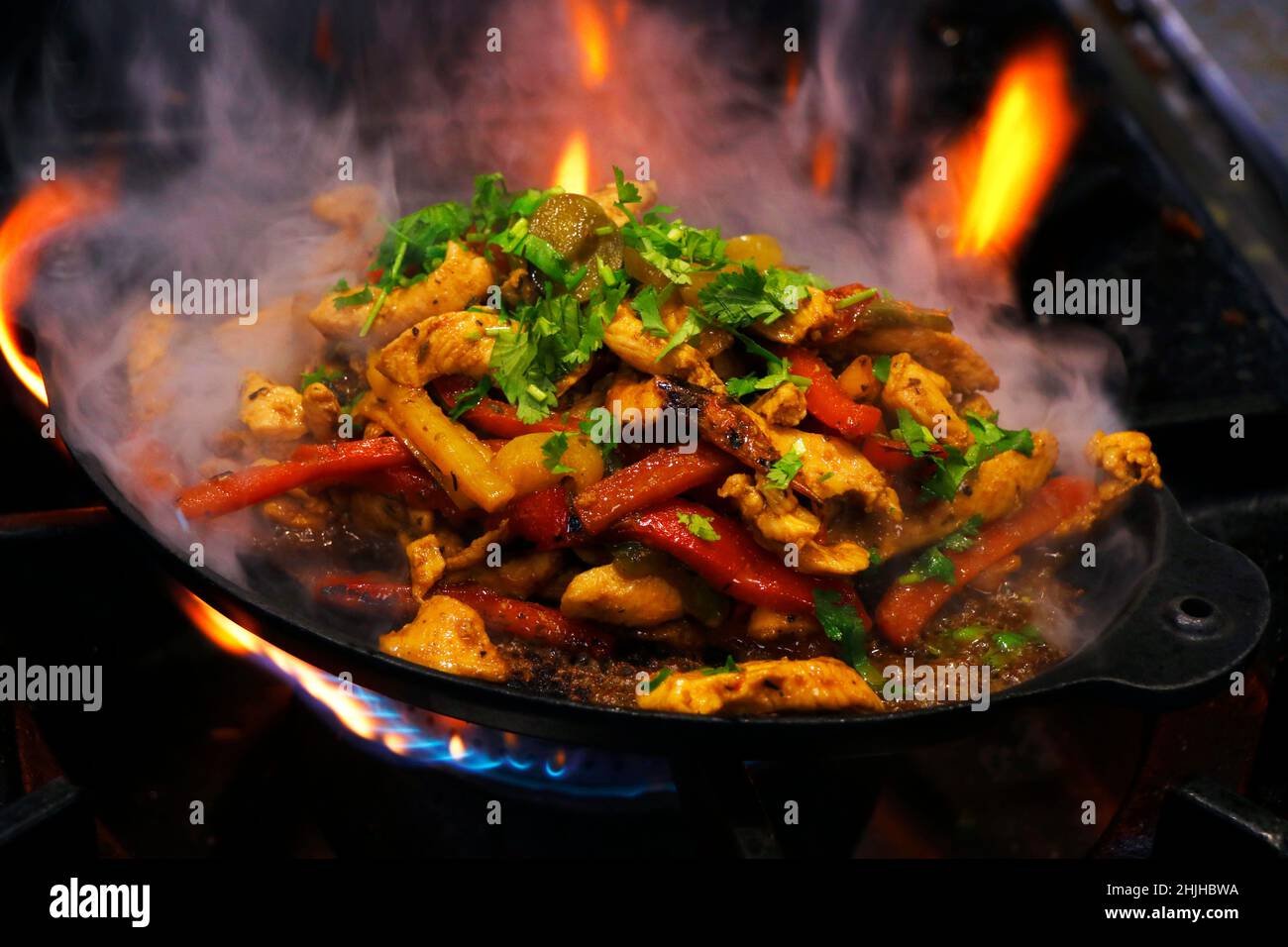 mexikanisches Essen, Hühnerfajitas auf einem heißen, rauchenden, brutzelnden Teller Stockfoto