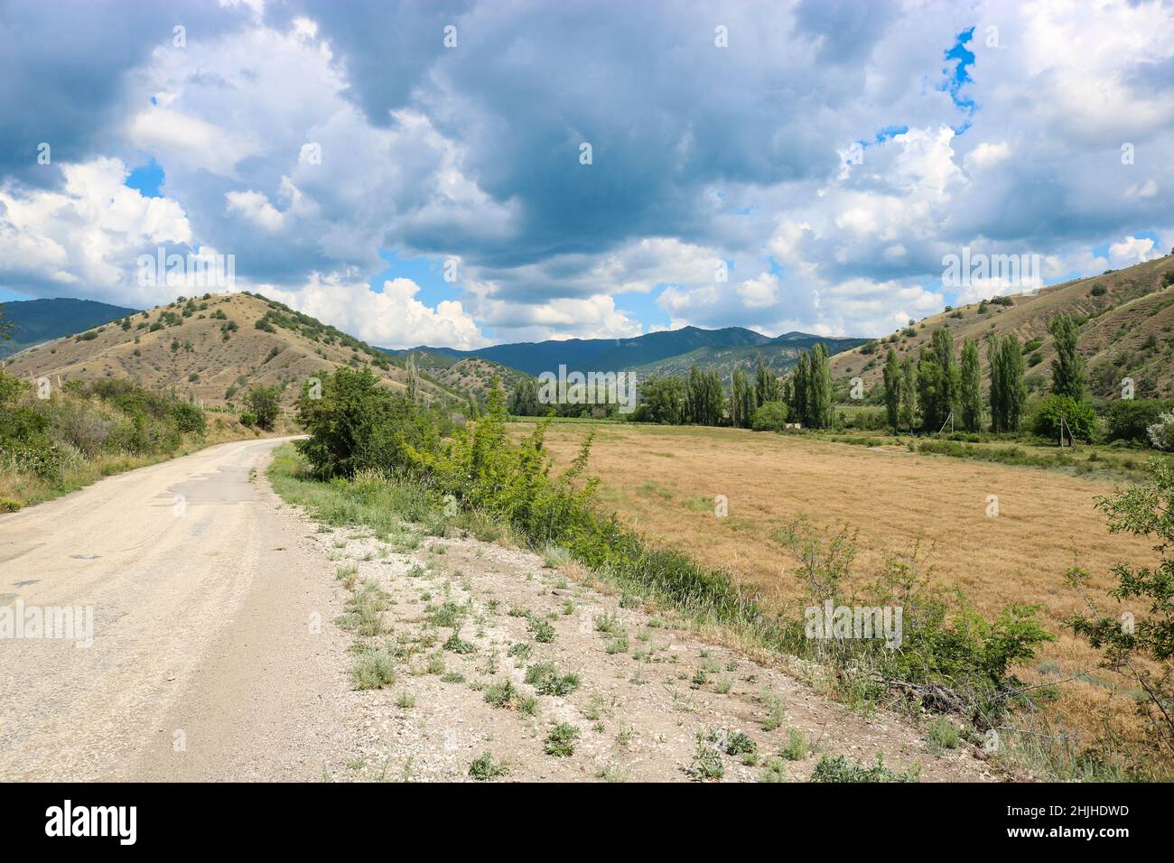 Schöne bergige ländliche Landschaft mit einer Straße, blauer Himmel mit niedrigen Cumulus Wolken. Stockfoto