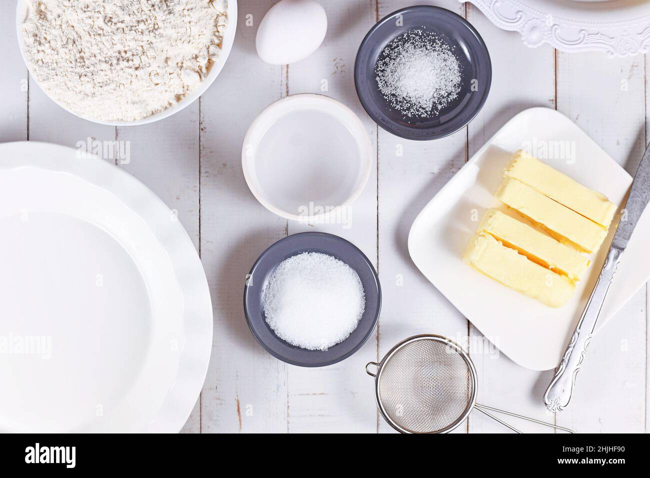 Zutaten aus Kuchenkruste in Schüsseln. Mehl, Zucker, Salz, Eiswasser, Butter und Ei auf Holztisch Stockfoto