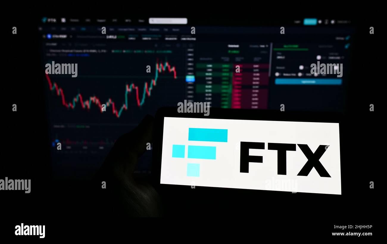 Person, die das Smartphone mit dem Logo des Kryptowährungsunternehmens FTX Trading auf dem Bildschirm vor der Website hält. Konzentrieren Sie sich auf die Telefonanzeige. Stockfoto