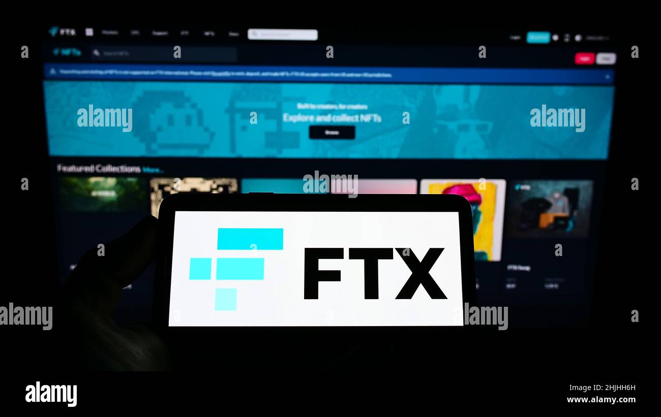 Person, die ein Mobiltelefon mit dem Logo des Kryptowährungsunternehmens FTX Trading auf dem Bildschirm vor der Webseite hält. Konzentrieren Sie sich auf die Telefonanzeige. Stockfoto