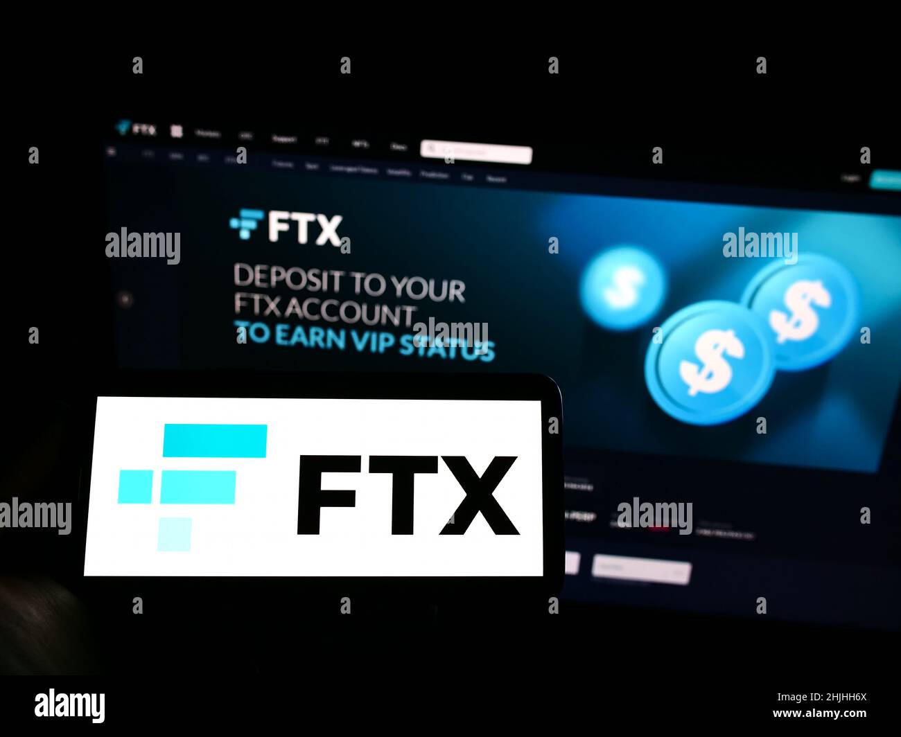 Person, die Mobiltelefon mit dem Logo der Kryptowährungsfirma FTX Trading auf dem Bildschirm vor der Business-Webseite hält. Konzentrieren Sie sich auf die Telefonanzeige. Stockfoto