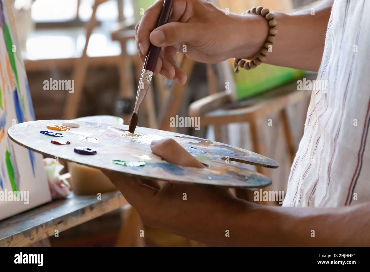 Künstler Hand hält Palette an Staffelei mit Öl, Acrylfarben Stockfoto