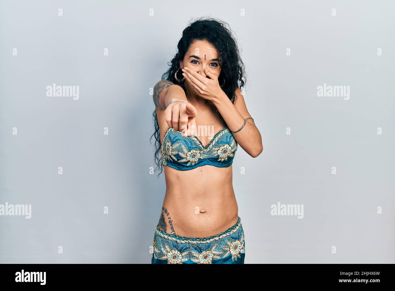 Junge Frau in Bindi- und traditionellen Bauchtanzkleidung, die Sie anlacht, mit dem Finger auf die Kamera zeigt, mit der Hand über dem Mund, Schamgefühl Stockfoto
