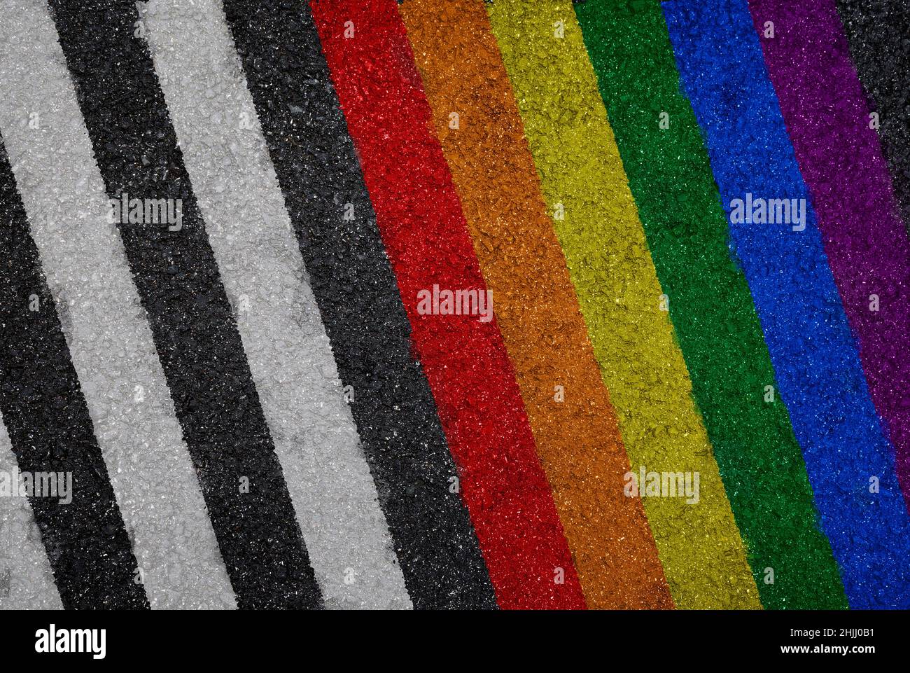 Regenbogenfarbene LGBT-Stolzflagge neben weißen Linien auf Asphalt, Draufsicht. Texturierter Hintergrund von bunt gestreiften Asphalt Hintergrund. Stockfoto
