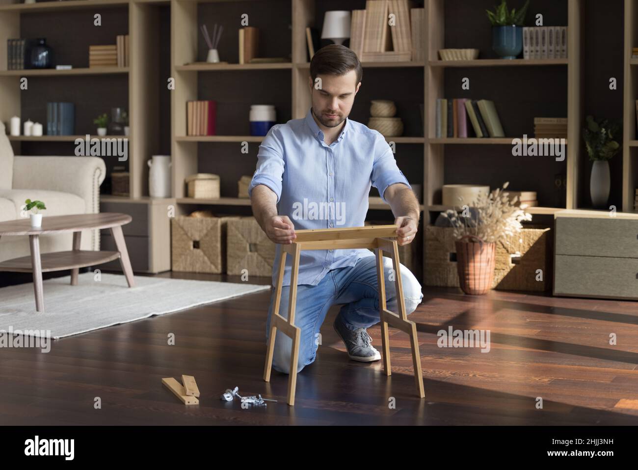 Konzentrierter junger männlicher Hausbesitzer, der kaputte Holzmöbel fixiert. Stockfoto