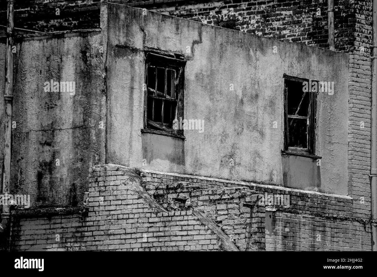 Graustufenaufnahme eines alten verlassenen Gebäudes mit kaputten Fenstern Stockfoto