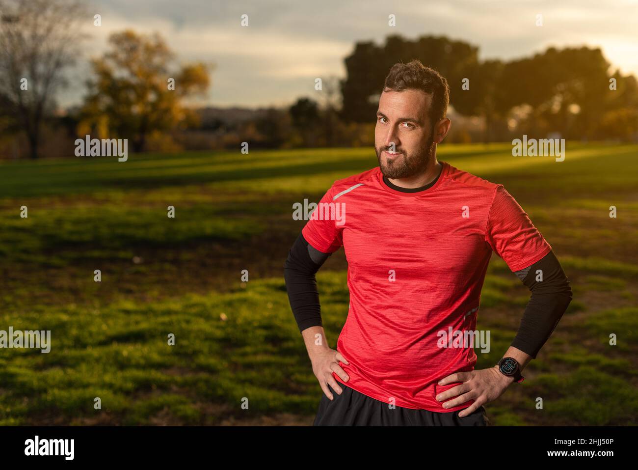 Selbstbewusster Sportler, der im Park mit den Händen auf der Hüfte steht Stockfoto