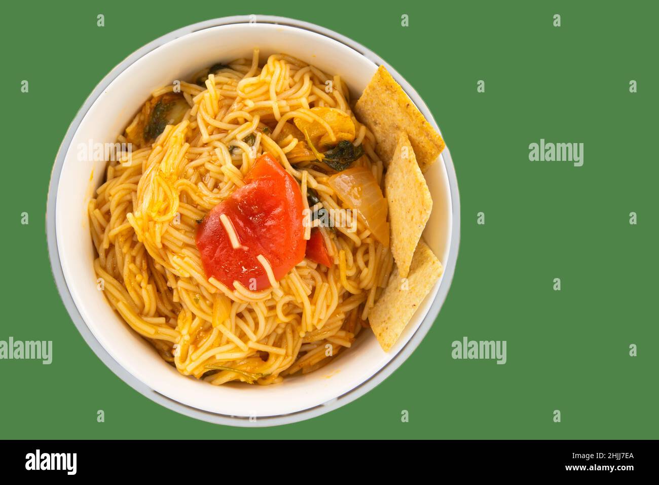 Draufsicht auf köstliche Nudeln mit Gemüse in einer Schüssel mit Tortilla-Chips auf grünem Hintergrund serviert Stockfoto