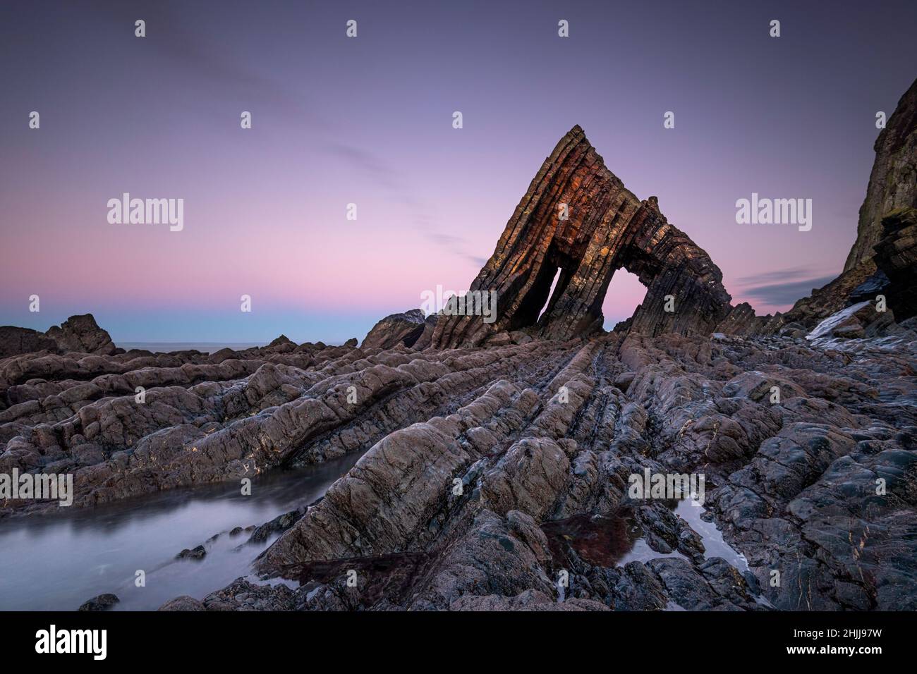 Der imposante Blackchurch Rock steht hoch am Mouthmill Beach in Devon bei Sonnenuntergang Stockfoto