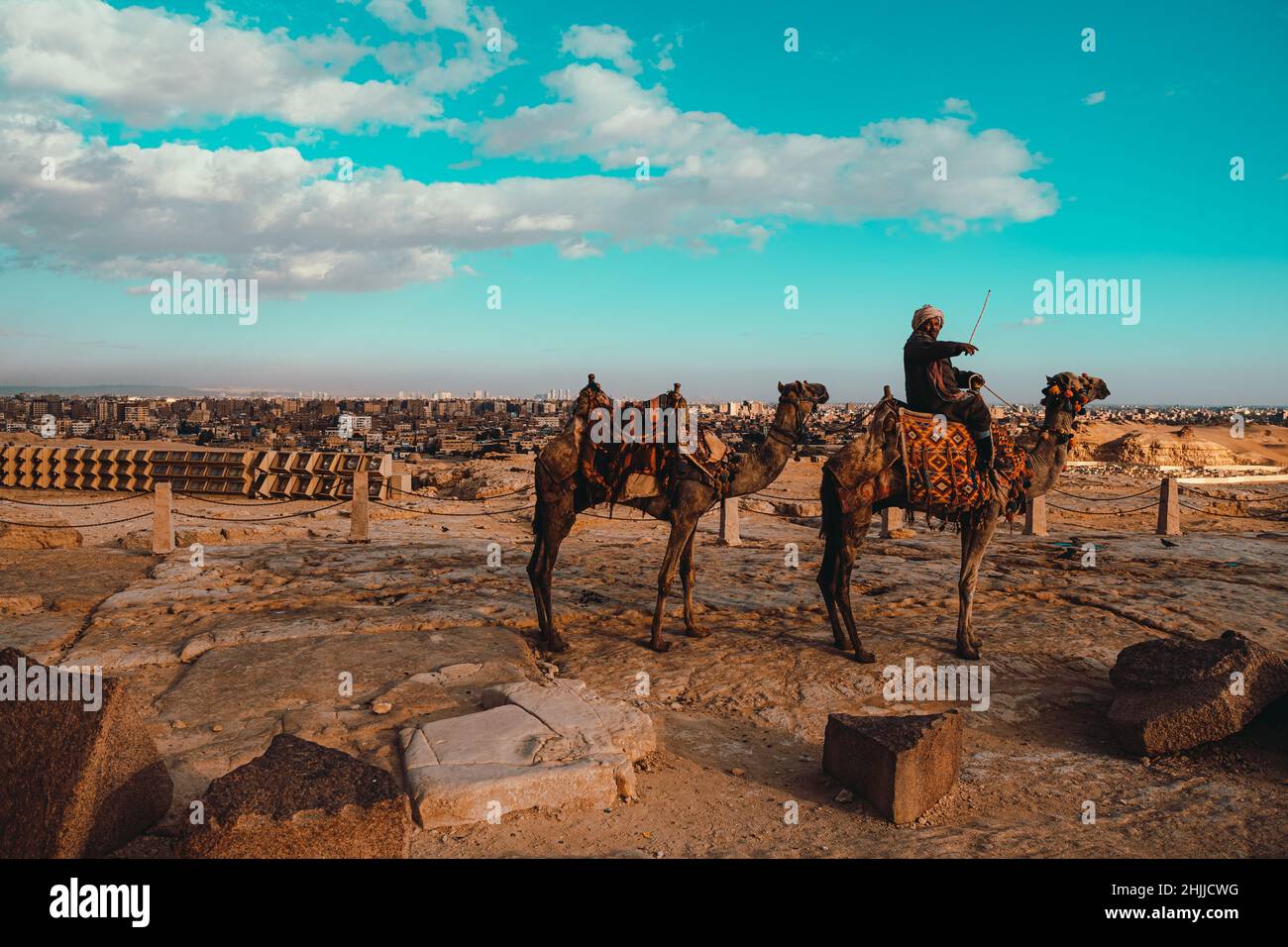 Kairo Ägypten Dezember 2021 Alter Mann auf einem Kamel winkt zur Kamera, Verkäufer versucht, Kamelreiten um die pyramiden von gizeh zu verkaufen Stockfoto
