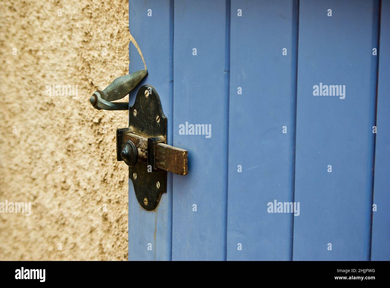 Gebäude aus gelbem Stein mit blauer Holzklappe und Verriegelungsvorrichtung in der Provence in Frankreich. Stockfoto