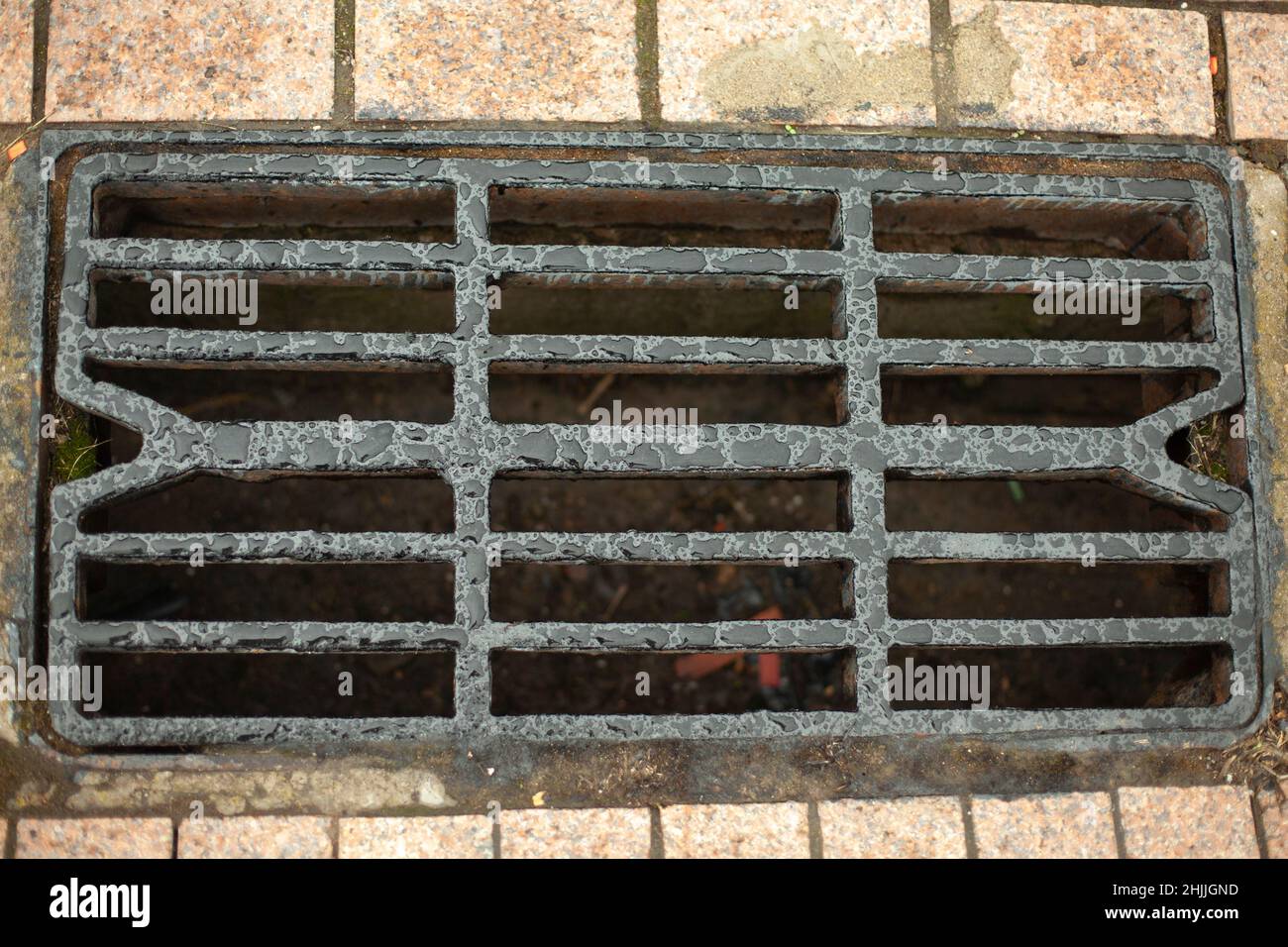 Sturmabfluss für die Wasserableitung. Details der städtischen Kommunikation. Luken des Kanals. Rost auf der Straße. Abfluss für Regenwasser. Stockfoto